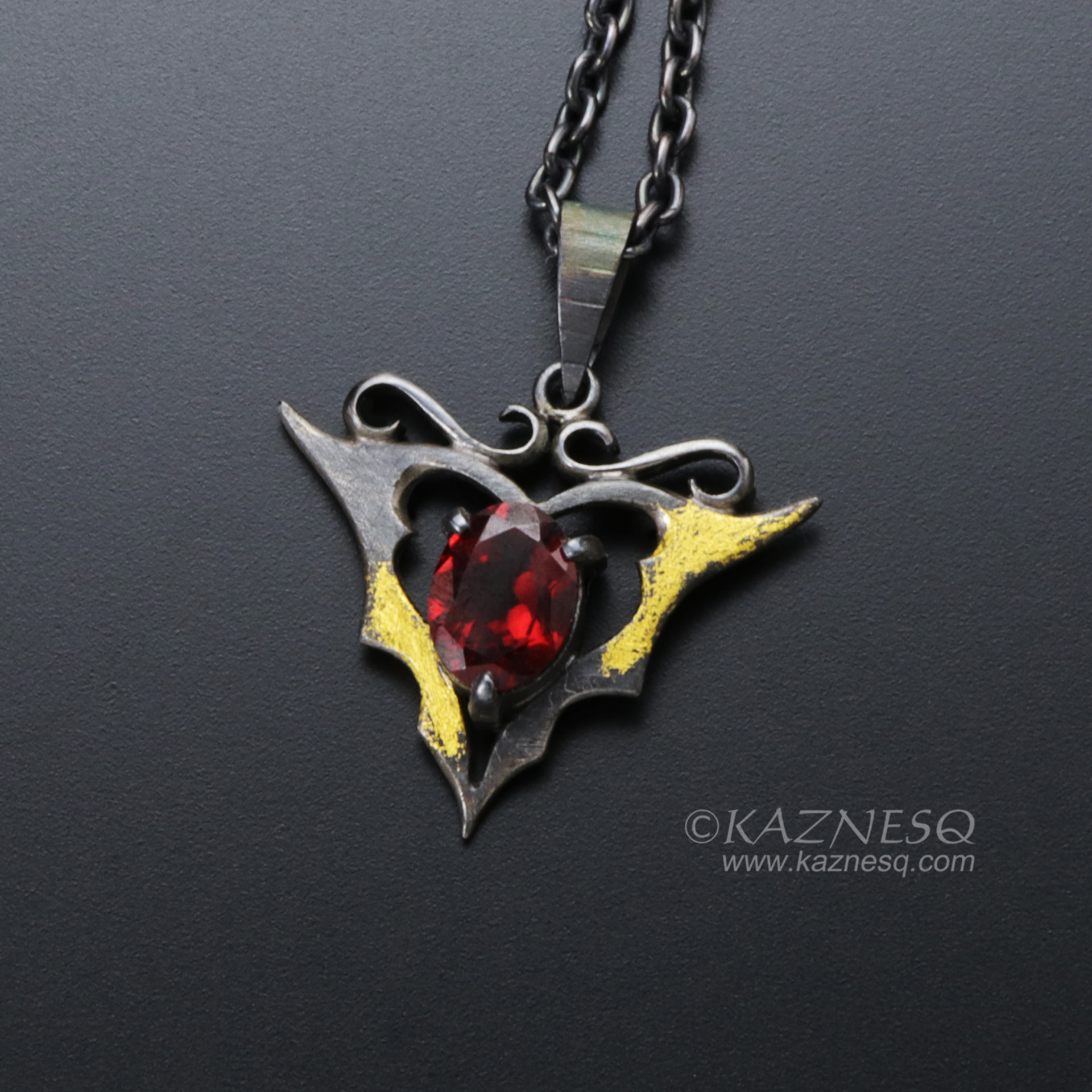 Goth taste silver pendant necklace with oval garnet and gold leaf
