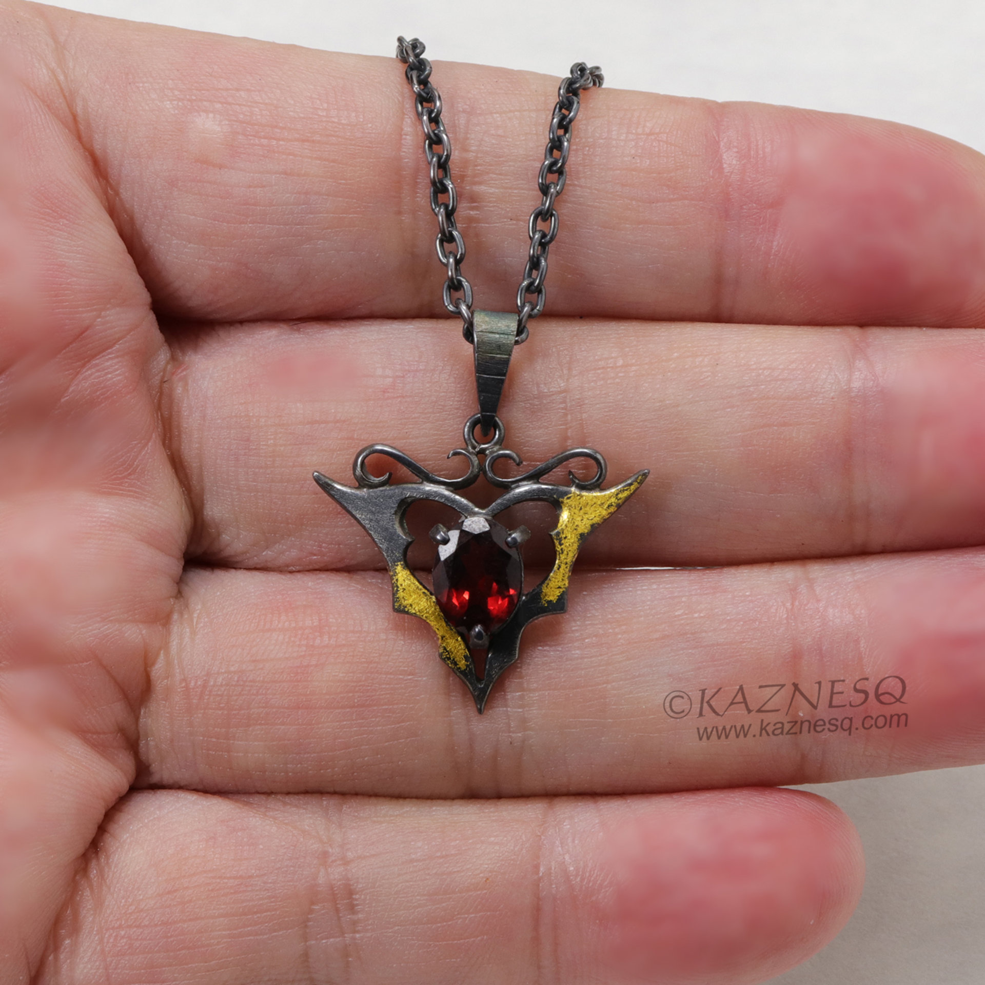 Goth taste silver pendant necklace with oval garnet and gold leaf